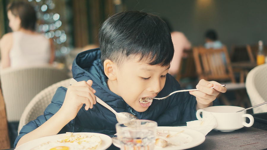 Boy eating food in restaurant