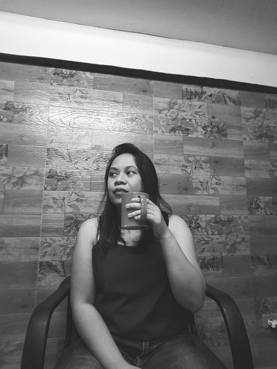 Portrait of young woman sitting against wall