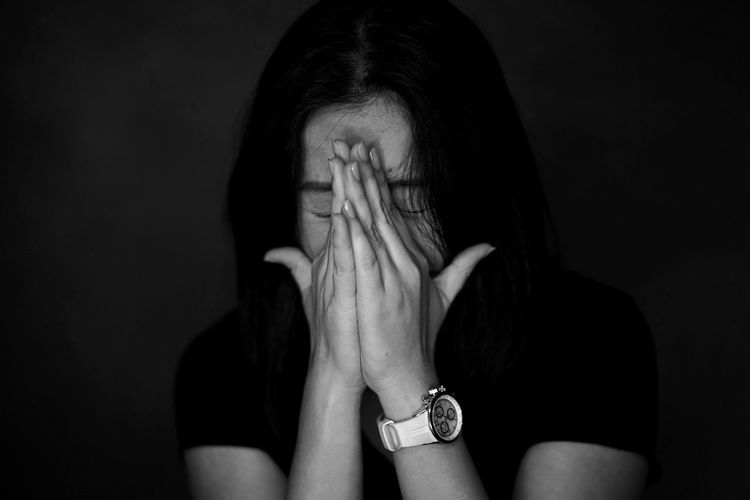 Close-up of woman crying against black background