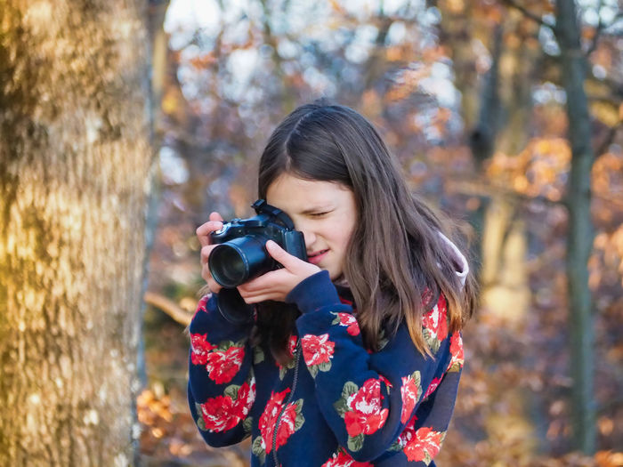 Girl photographing with camera in forest