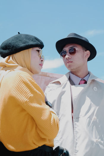 Fashionable couple wearing hats and warm clothing in city