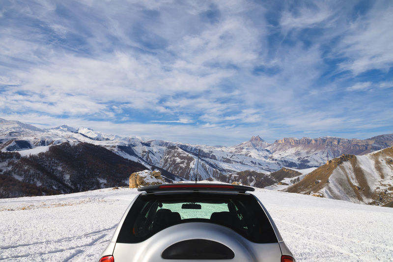 Rear view of the unrecognizable upper part of an suv high in the mountains in winter against 