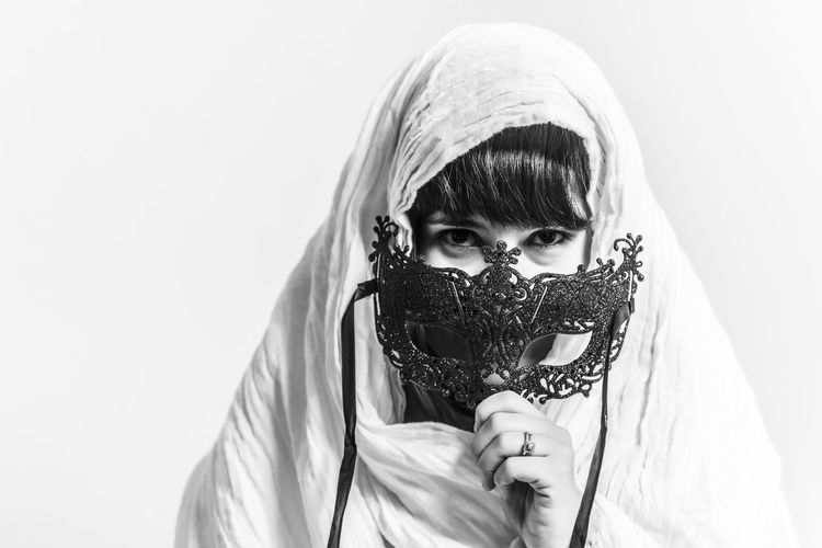 Portrait of woman holding eye mask against white background