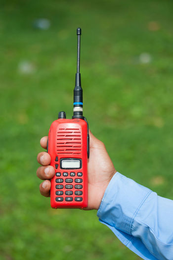 Close-up of hand holding walkie-talkie over field