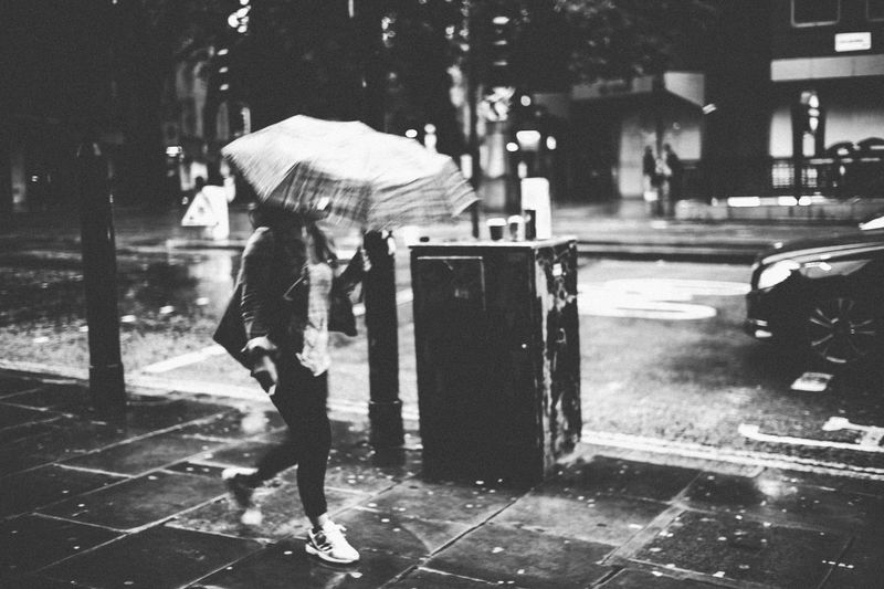 Full length of woman walking on sidewalk with umbrella