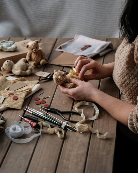 A young woman sews a teddy bear. hobby
