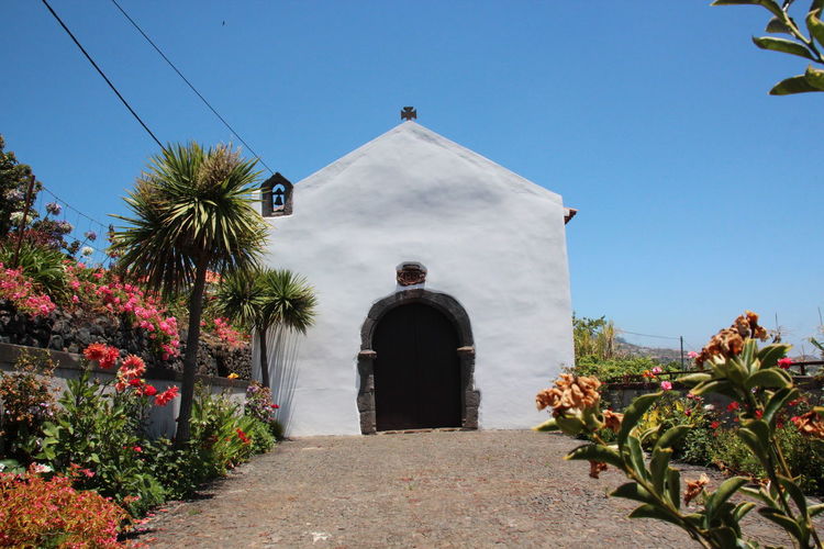 Closed door of chapel amidst plants against sky