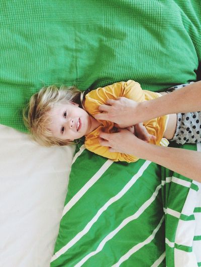 Cropped image of hands tickling girl on bed