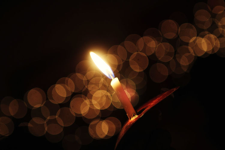 Tilt shot of burning candle in dark