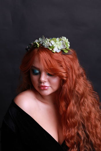 Sensuous young woman wearing wreath against black background