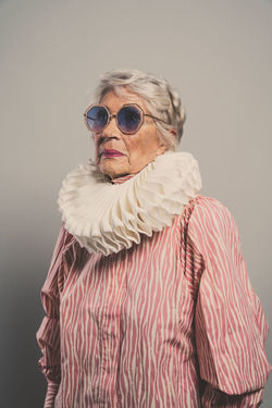 portrait of woman wearing sunglasses standing against gray background