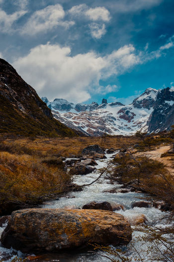 Scenic view of stream against snowcapped mountains and sky
