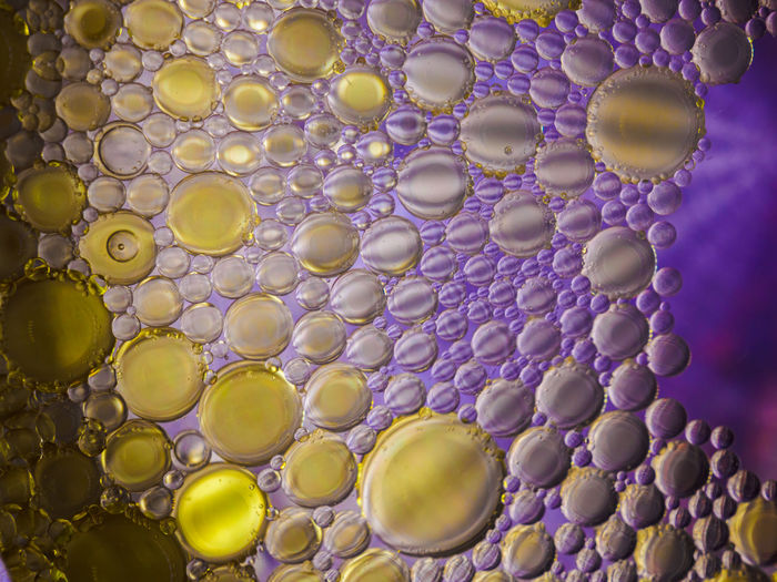 Colorful macro shot of olive oil bubbles in a colored glass of water