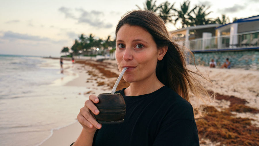 Young woman drinking water at beach