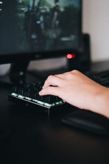 Cropped hand playing game on computer