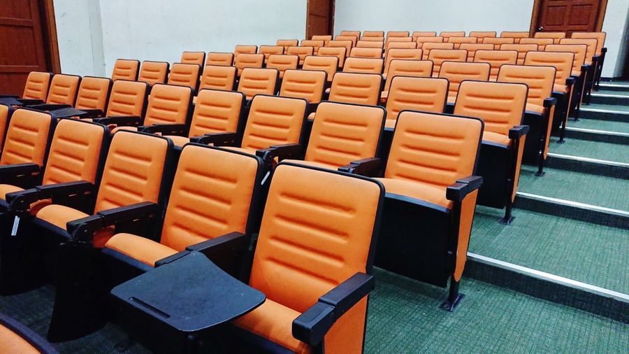 Empty orange chairs in auditorium
