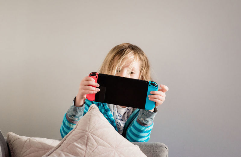 Young girl playing nintendo switch at home on the sofa