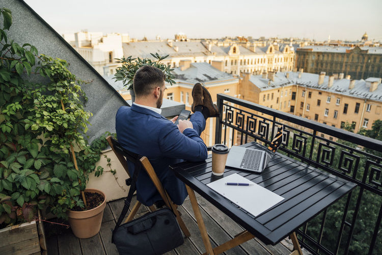 Male professional using smart phone in office balcony