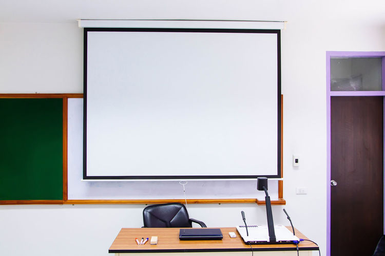 Projection screen hanging on wall in classroom