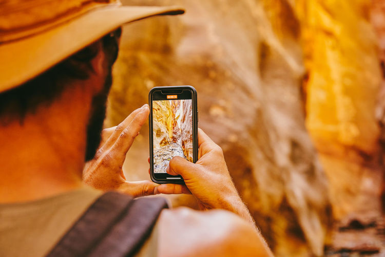 Young man wearing hat taking picture of slot canyons in kanarra falls