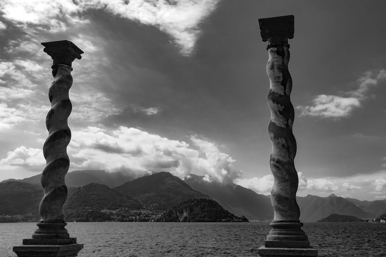 Statue against sea and mountains against sky