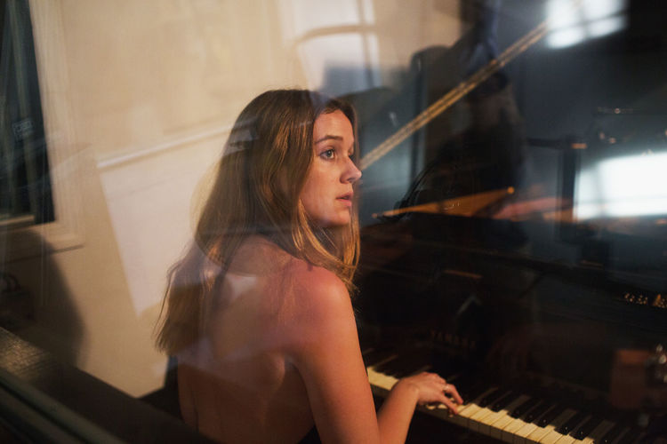 Young woman playing piano at a recording studio