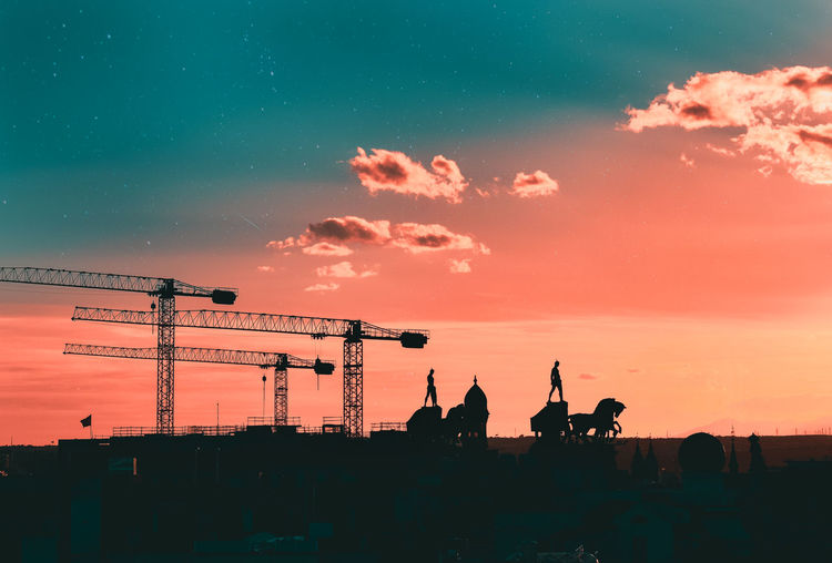 Silhouettes of cranes, statues and buildings of madrid, with a creative sky. madrid