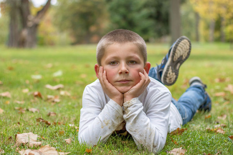 Portrait of cute boy lying on grass during autumn