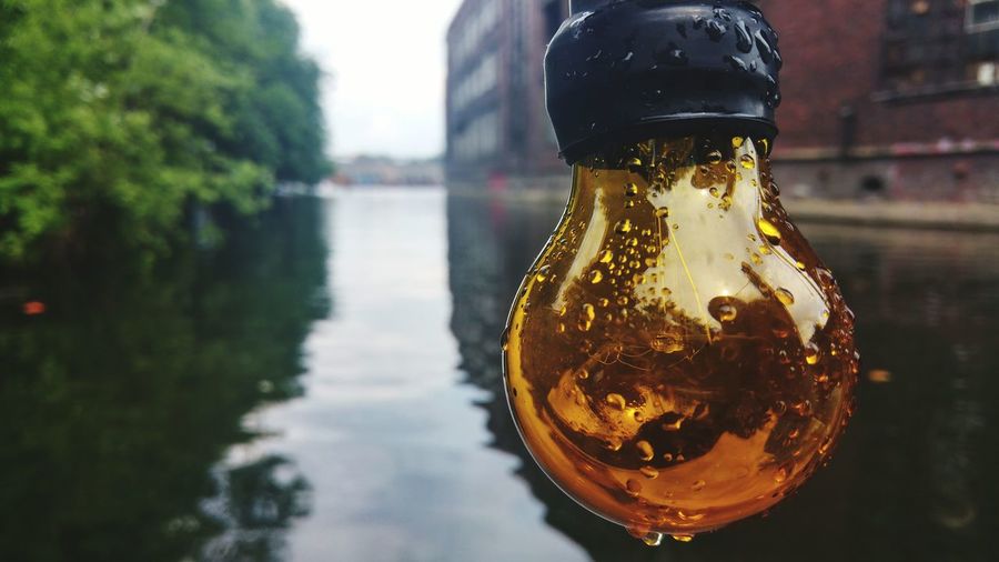 Close-up of glass bottle against river
