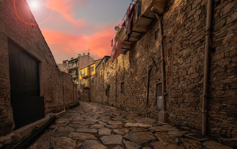 Narrow alley amidst buildings during sunset