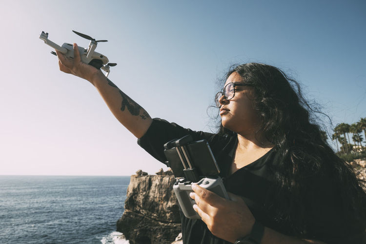 Happy woman with drone looking to the side and remote control by sunny day technological concept