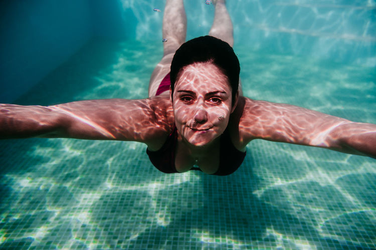 Portrait of woman swimming underwater in pool