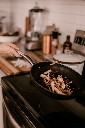 Cropped hand of person preparing food in kitchen at home