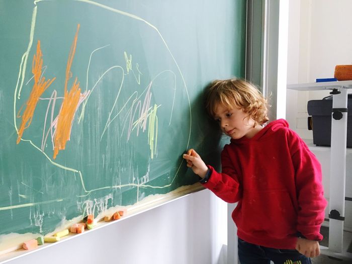 Cute girl drawing on blackboard