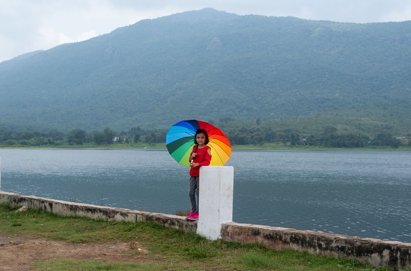 Person standing by lake against mountains