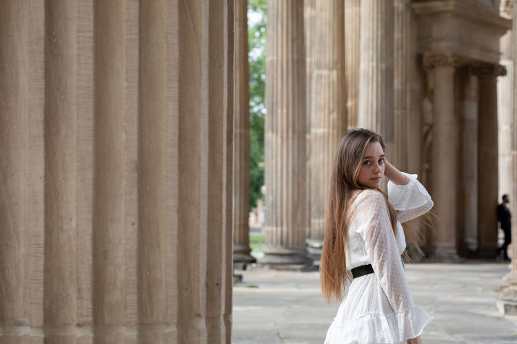 Portrait of young woman standing against columns