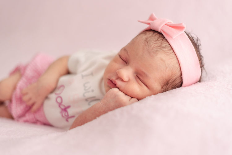A newborn baby girl with a headband sleeping peacefully. newborn session concept
