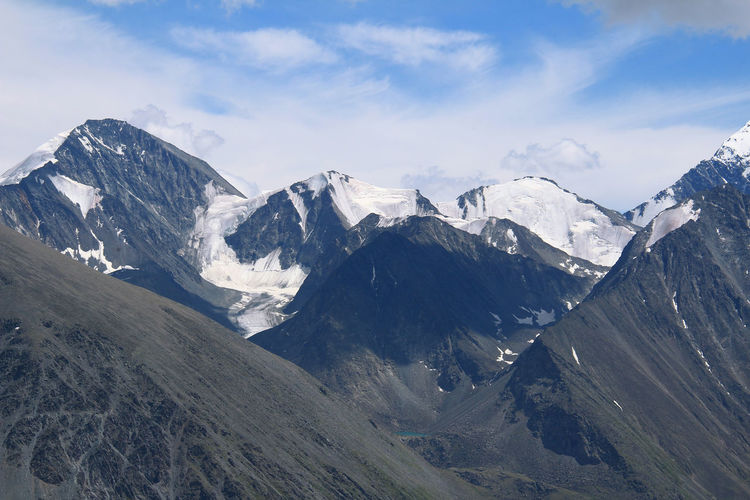 Rocky high mountain peaks with glacier and snow on the background of the sky with clouds