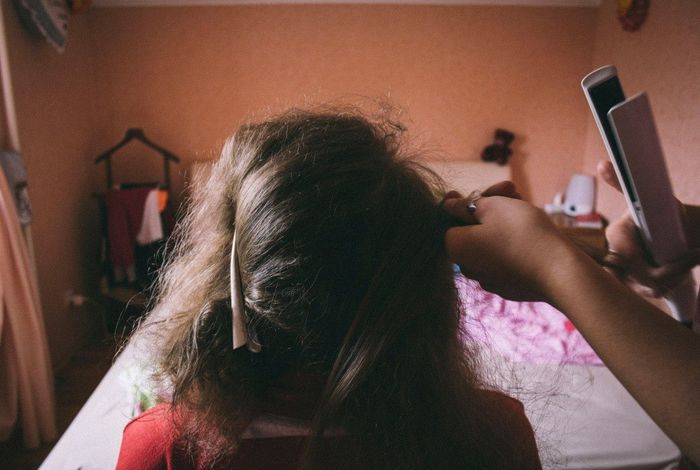 Young women using hair straighteners