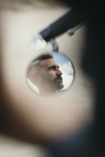 Reflection of man with beard on bike mirror