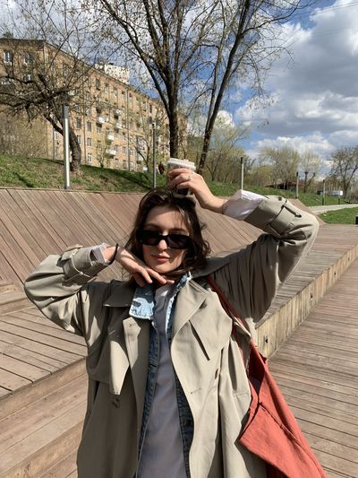 Girl wearing trench coat and sunglasses in spring during coffee break 