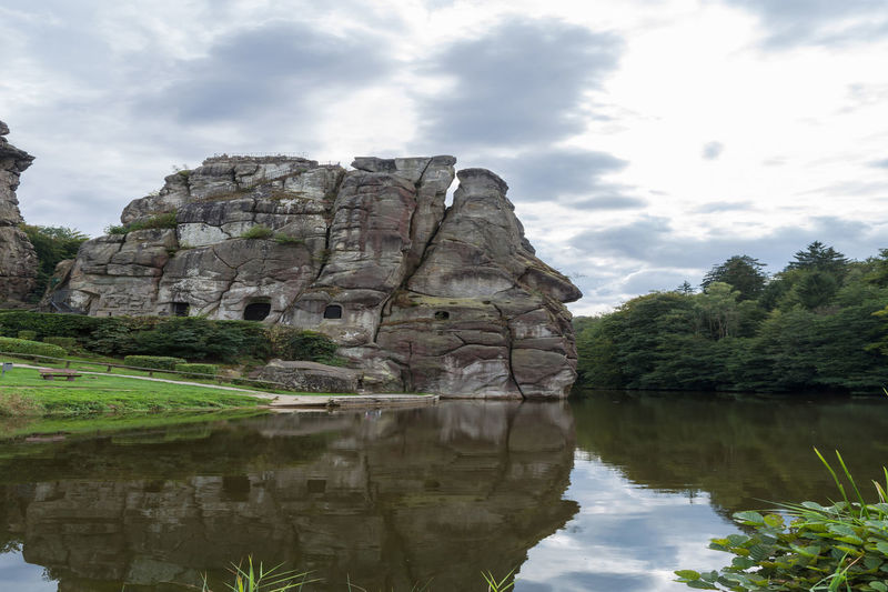 Rock formation by lake against sky