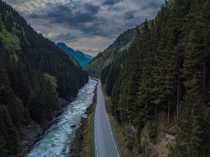 Stream flowing amidst mountains against cloudy sky during sunset