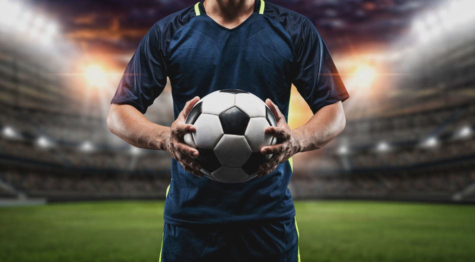Man holding ball while sitting on soccer field