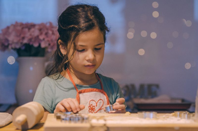 Close-up of girl making cookies on table at home