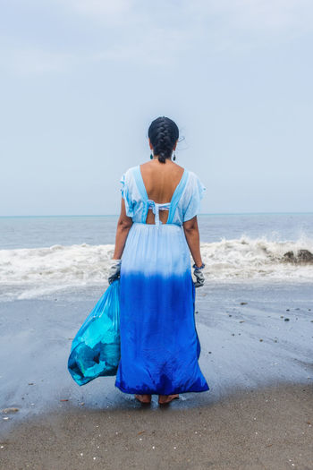 Young woman with garbage bag on her back on the beach. beach cleaning concept