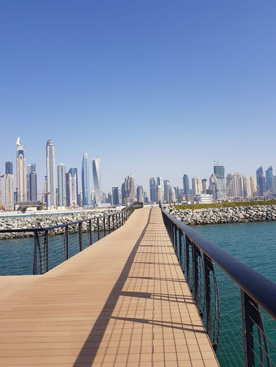 Modern buildings by sea against clear sky