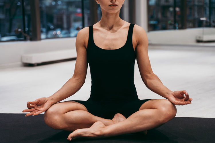 Low section of woman meditating at gym