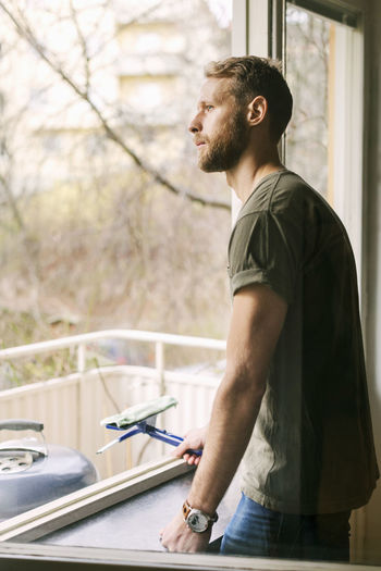 Side view of thoughtful man looking through window