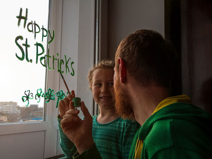 Drawing st. patrick's day father daughter painting green three-leaved shamrocks.stay home new normal